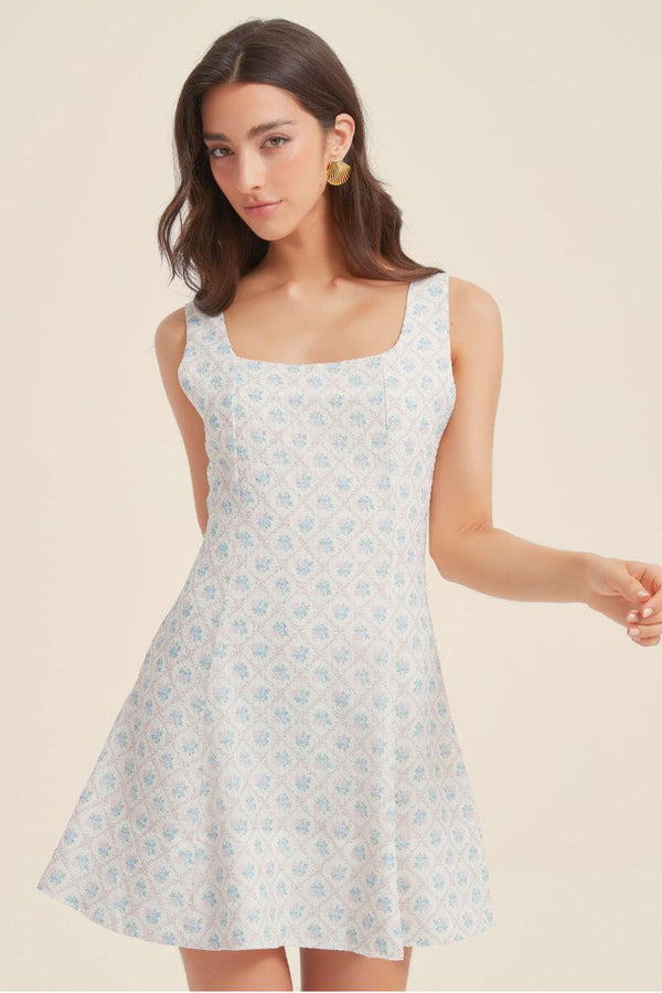 Close-up of the blue jacquard floral mini dress showing the textured floral pattern, square neckline, and soft pastel detailing.