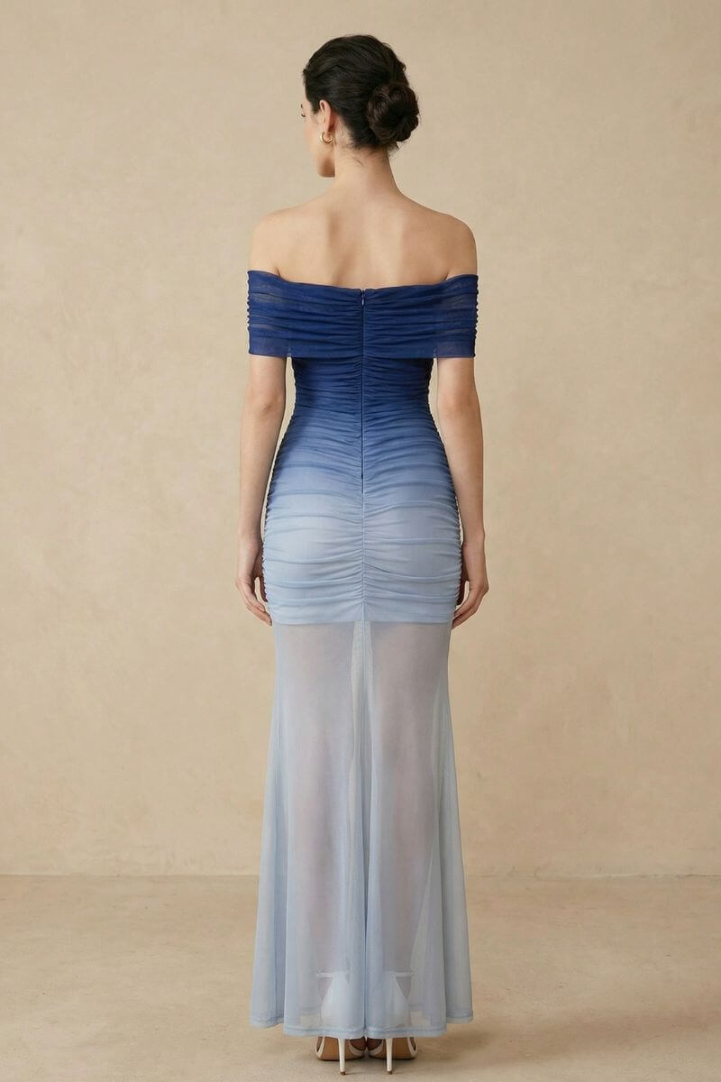 Back view of a blue ombre off-shoulder mesh maxi dress showing ruched detailing and a sheer flared hem, photographed in a minimal studio setting.