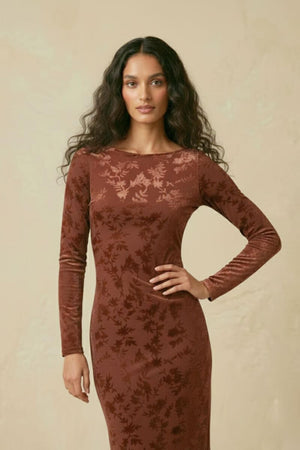 A close-up of a brown burnout velvet midi dress showing the long sleeves, fitted bodice, and subtle floral burnout pattern.