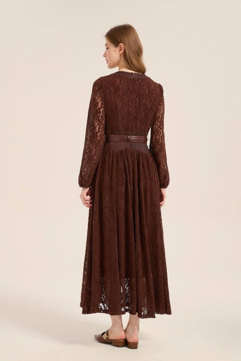 Model showing the back of a brown lace long sleeve maxi dress with a belted waist and full lace overlay, styled with brown flats.