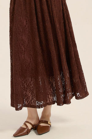Close-up view of brown lace dress hemline showcasing floral lace pattern and sheer texture over lining.