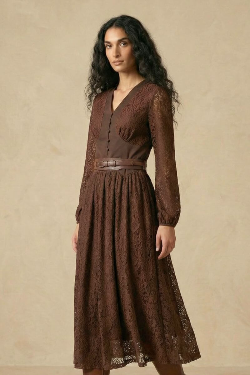 A woman in a brown lace long-sleeve midi dress with a V-neck structured bodice, decorative buttons, and a wide leather waist belt, shown from an angled front pose.