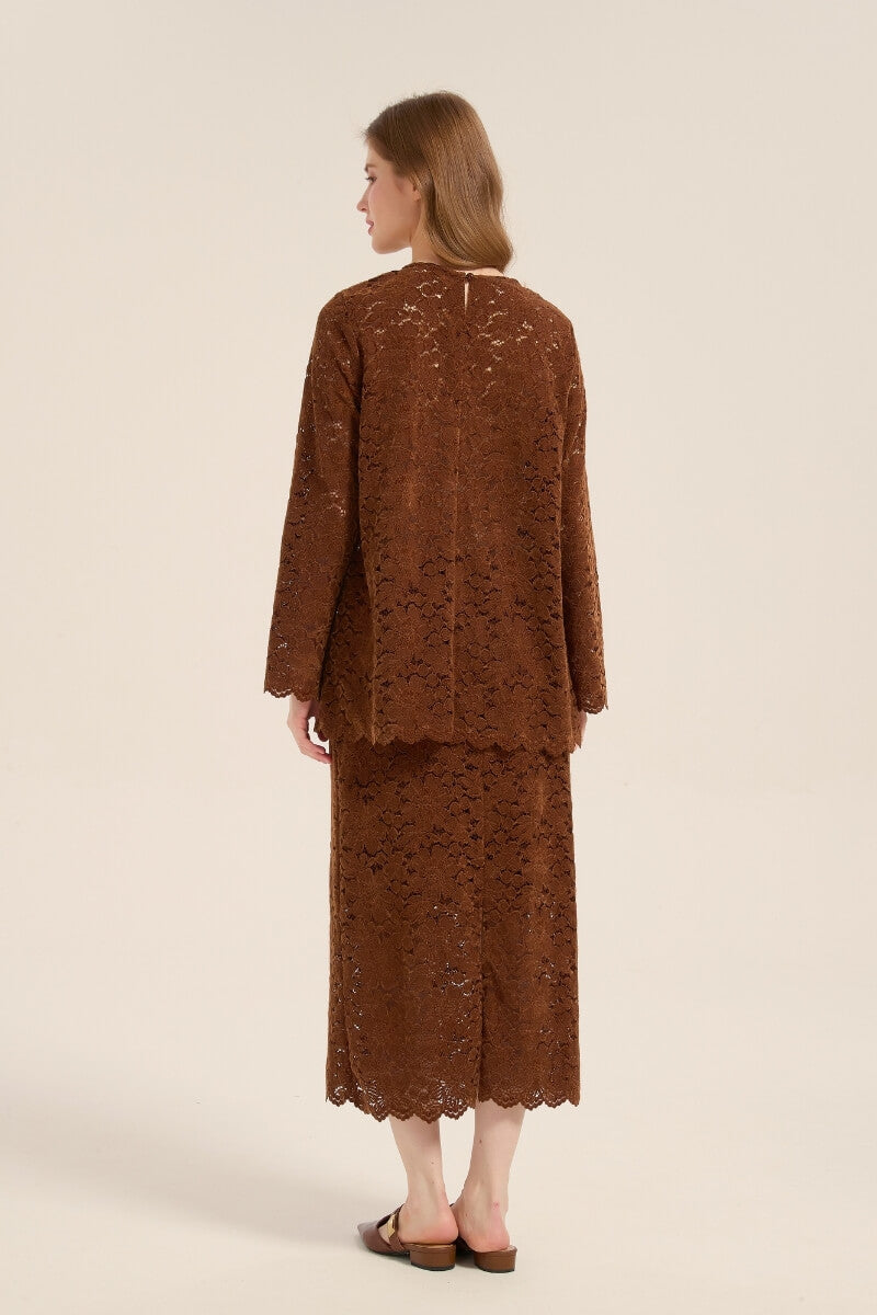 Model wearing a brown lace two-piece outfit from behind, featuring long-sleeve top and midi skirt with scalloped edges and relaxed silhouette.