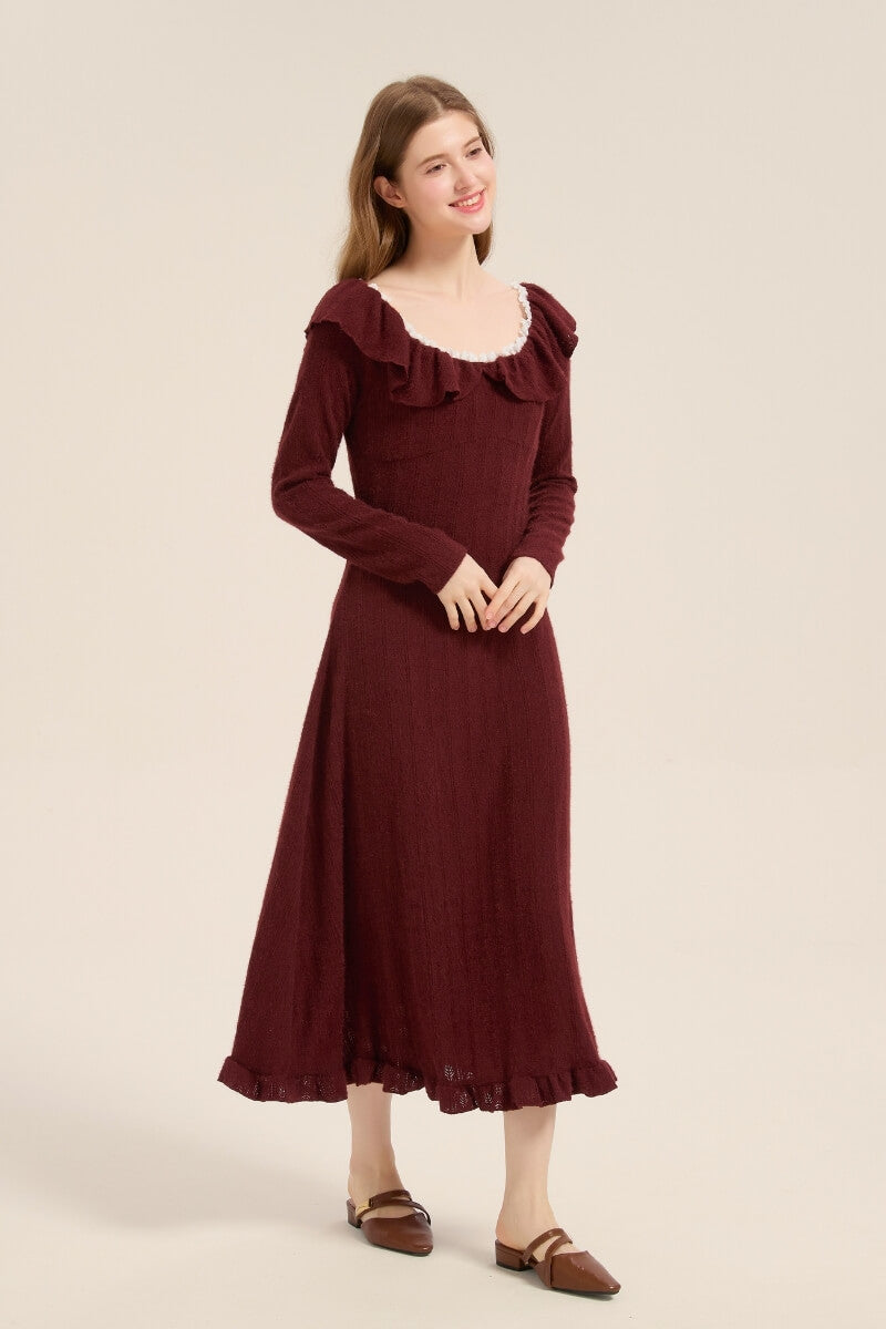 Model posing in a burgundy knit ruffle midi dress featuring a soft texture, long sleeves, and flounce hem, styled with brown flats.