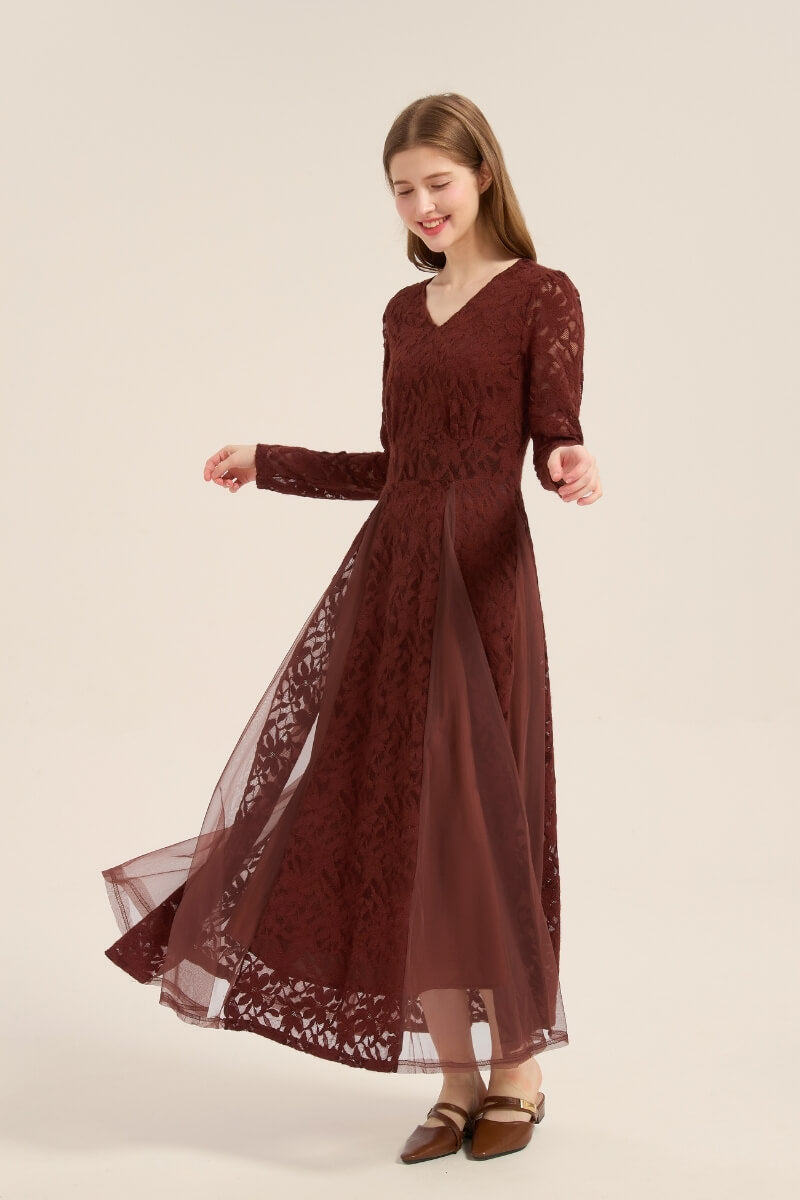 Model twirling in a burgundy lace long sleeve maxi dress featuring sheer mesh panels and soft V-neckline, exuding romantic charm.