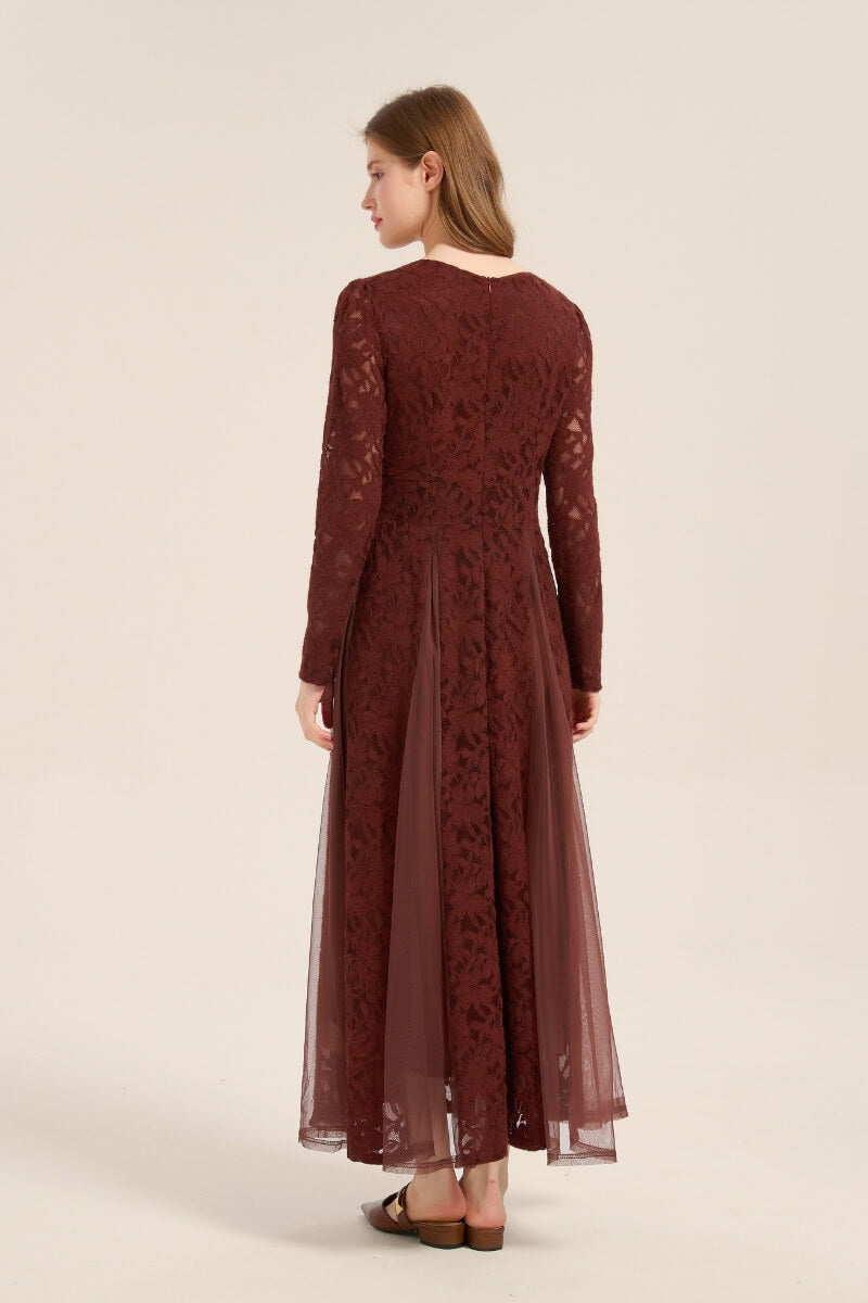 Model turned to show the back of a burgundy lace maxi dress with sheer mesh panels, long sleeves, and V-shaped neckline.