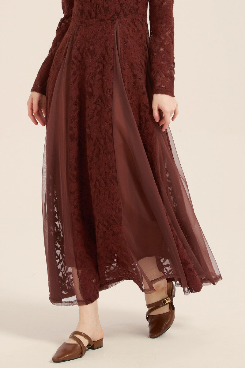 Close-up of burgundy lace maxi dress showing sheer mesh panels and floral lace texture, styled with brown flats for an elegant finish.