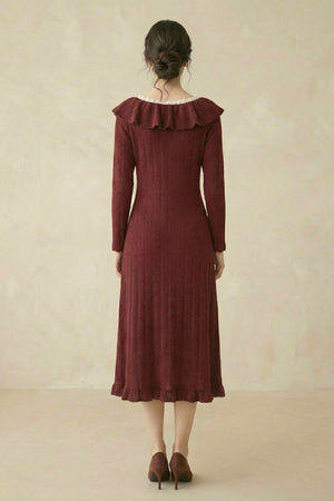 A woman shown from the back wearing a burgundy long-sleeve textured knit midi dress with a ruffled neckline and a softly flared hem.