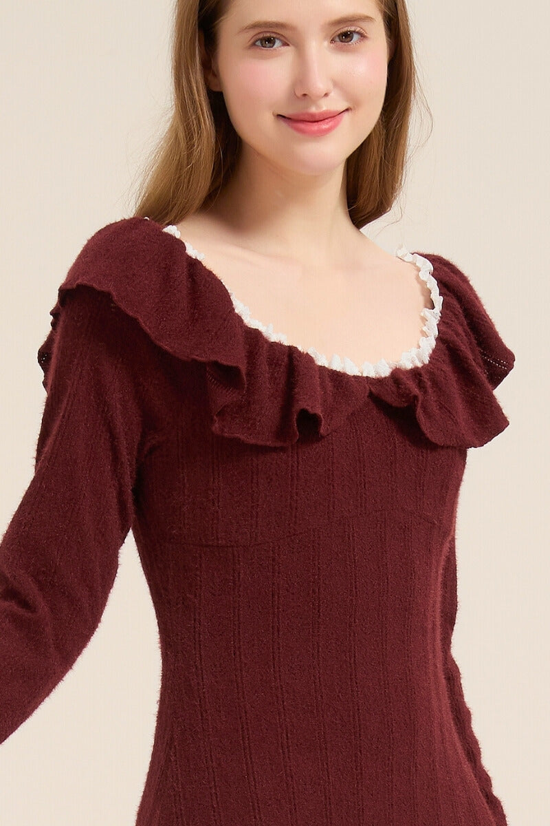 Close-up of model wearing a burgundy knit midi dress with white ruffle trim around the neckline and soft textured knit fabric.