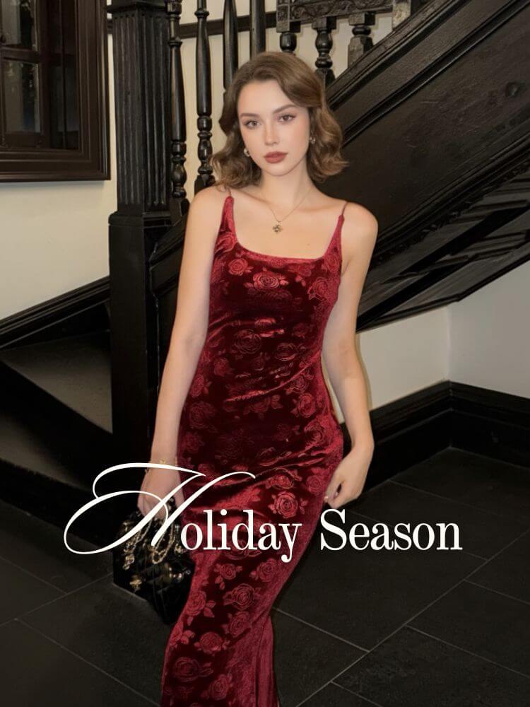 Woman wearing a burgundy velvet maxi dress with a rose-embossed texture, styled in a vintage stairwell setting — perfect for elegant holiday evenings.