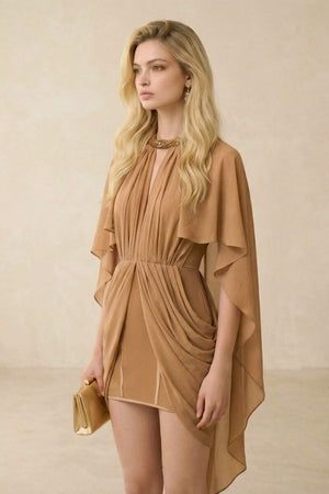Model wearing a camel chiffon mini dress with a pleated bodice, cinched waist, and sheer cape sleeves, styled with gold earrings and a metallic clutch in a warm-toned studio setting.