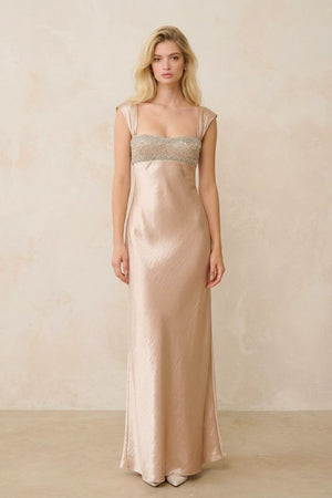 A full-length view shows a champagne satin maxi dress with wide straps and a beaded bodice, creating an elegant, fluid silhouette on a blonde model.