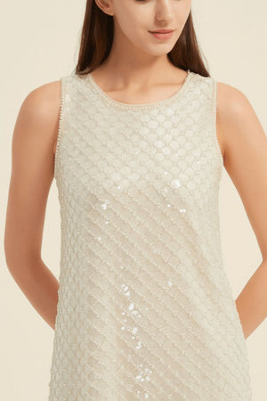 Close-up of the neckline and fabric texture of a champagne sequin mini dress with delicate pearl-beaded trim.
