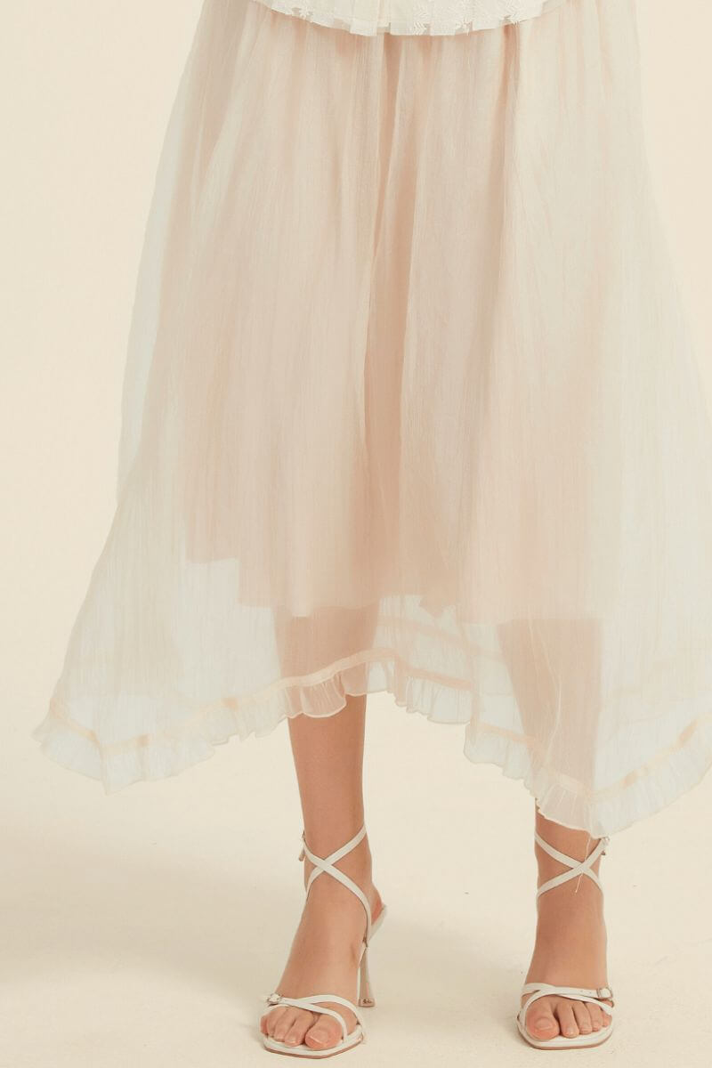 Detailed close-up of sheer ivory midi skirt showing light crinkled texture, double layered design, and romantic ruffled hemline.