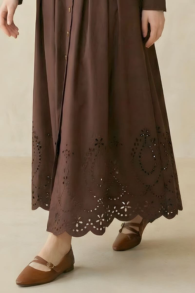 A close-up of a coffee brown shirt-style midi dress showing the scalloped eyelet hem with floral cutout detailing.