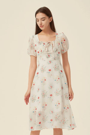 Model wearing a cream floral midi dress featuring a square neckline with tie detail, puff sleeves, and a soft flared hem — a vintage-inspired summer look by Sioéne.