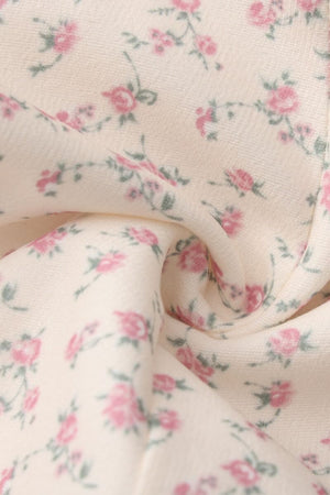 Close-up of cream fabric with soft pink floral print, showing the delicate vintage-inspired texture and pattern of the dress.