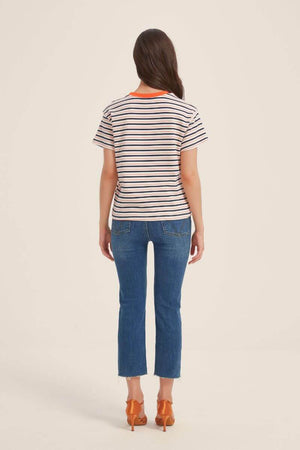 Back view of a cream T-shirt with navy and orange horizontal stripes and contrast orange neckline, styled with cropped blue jeans and orange heels.