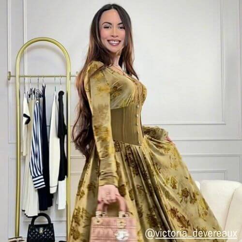 Woman in a golden velvet corset maxi dress from Sioéne posing indoors with a blush handbag — vintage-inspired fall outfit with luxurious texture and soft sheen.