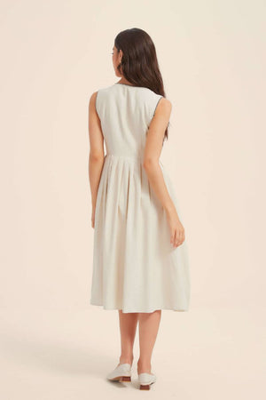 Back view of a sleeveless ivory button-down midi dress with a softly gathered waist and minimal silhouette, styled with white flats for a refined summer look.