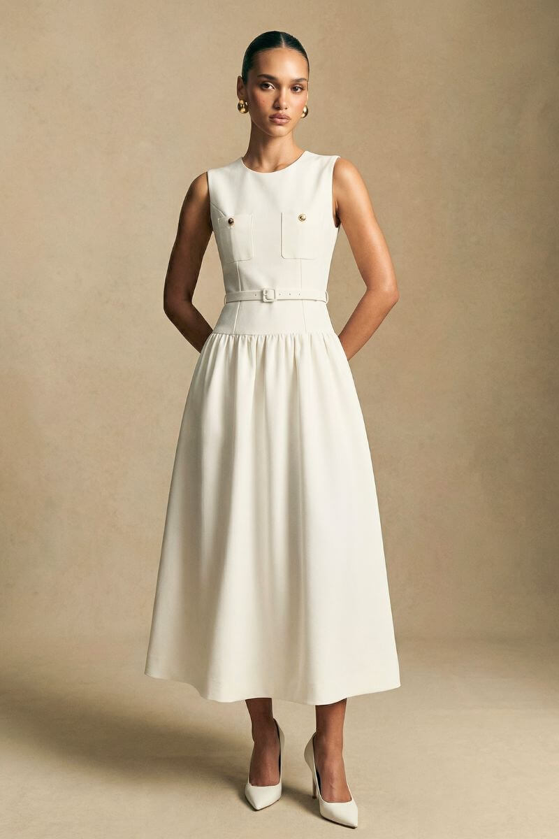 Side view of a model wearing an ivory halter maxi dress with raised floral embroidery, emphasizing the sleek profile and refined tailoring.