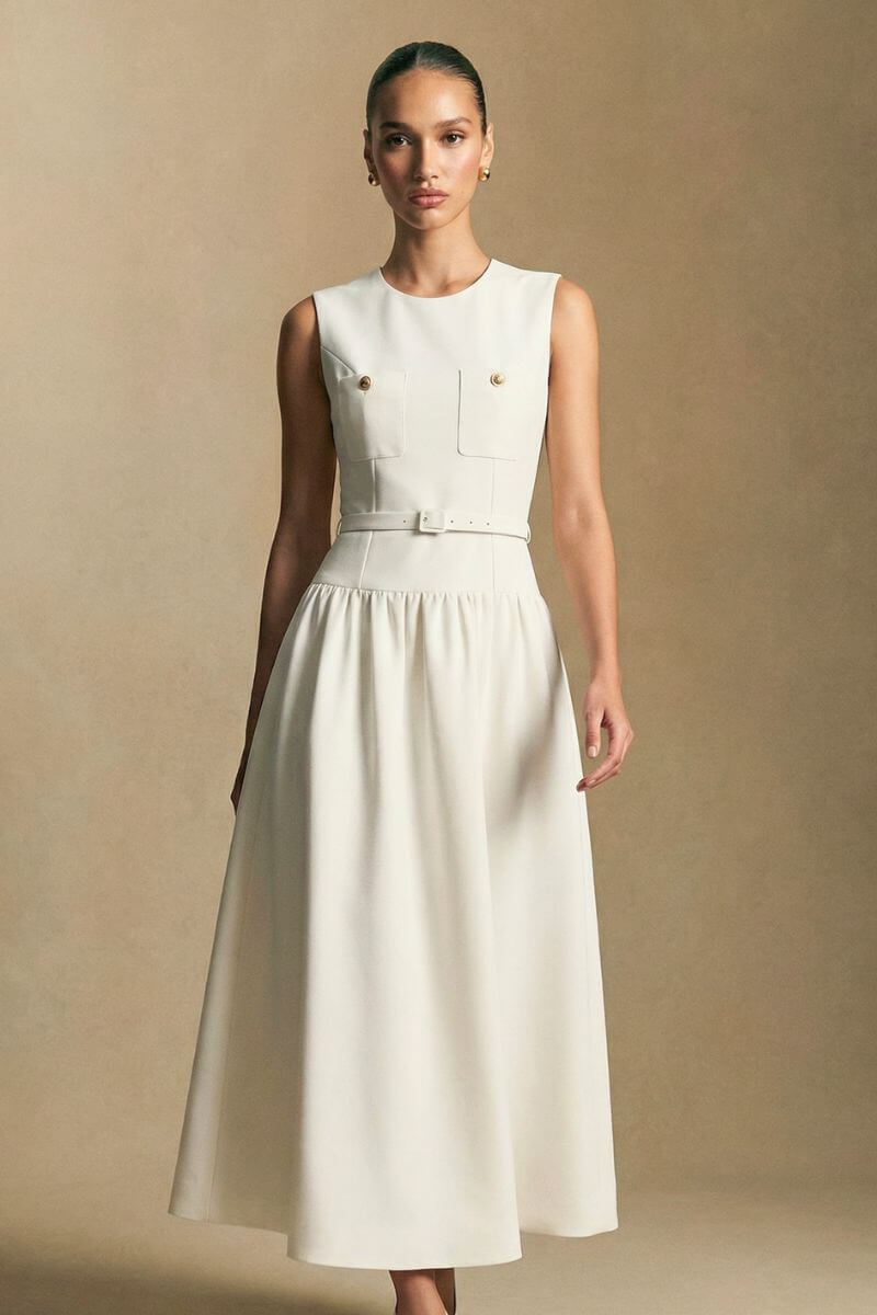 Model in motion wearing an ivory embroidered halter maxi dress, capturing the fluid hemline and subtle texture under soft studio lighting.