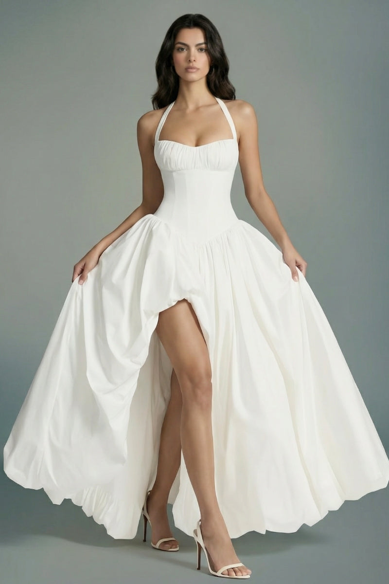 Model lifts the skirt of an ivory halter corset maxi dress to reveal its airy volume and fluid drape, emphasizing the romantic movement of the design.