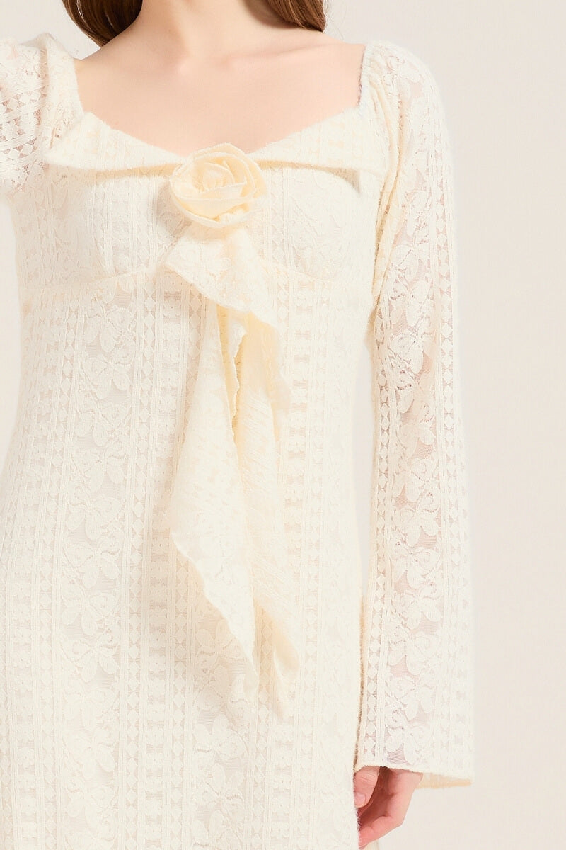 Close-up of the ivory lace midi dress showing a soft floral lace texture and large bow with rosette accent at the chest.