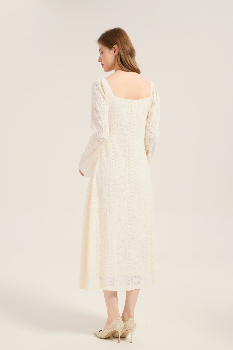 Model turned to show the back of an ivory lace midi dress with square neckline and fitted lace pattern throughout, styled with beige heels.