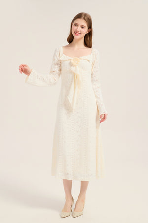 Model smiling in an ivory lace midi dress featuring a large bow with rose detail at the neckline, square collar, and long flared sleeves.
