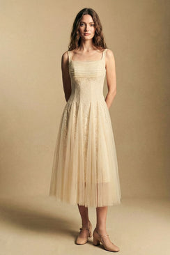 Model wearing an ivory lace midi dress with a fitted lace bodice and airy tulle skirt that falls below the knee, styled with nude Mary Jane heels in a minimalist studio environment.