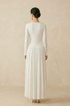 Back view of an ivory long sleeve maxi dress showing a clean silhouette, flowing skirt, and elegant drape from shoulder to hem.