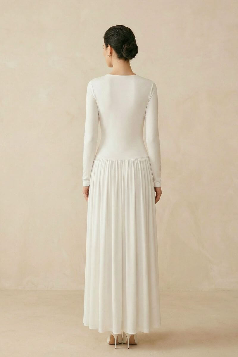 Back view of an ivory long sleeve maxi dress showing a clean silhouette, flowing skirt, and elegant drape from shoulder to hem.