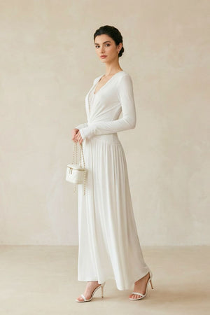 Side view of an ivory long sleeve maxi dress showing its fluid skirt movement, ruched waistline, and elegant lace neckline.