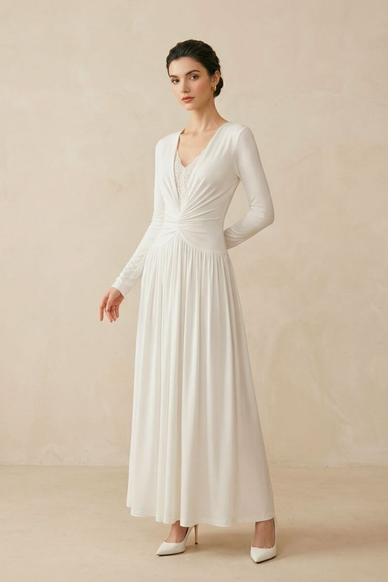 A model in an ivory long sleeve maxi dress featuring a twisted ruched waist and lace inset neckline, posed gracefully in a minimalist studio setting.