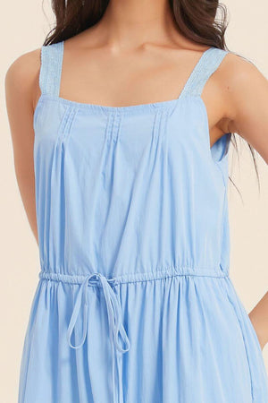 Close-up of a light blue sleeveless midi dress featuring lace-trim shoulder straps, soft pintuck pleats, and a gathered drawstring waist for an airy summer feel.