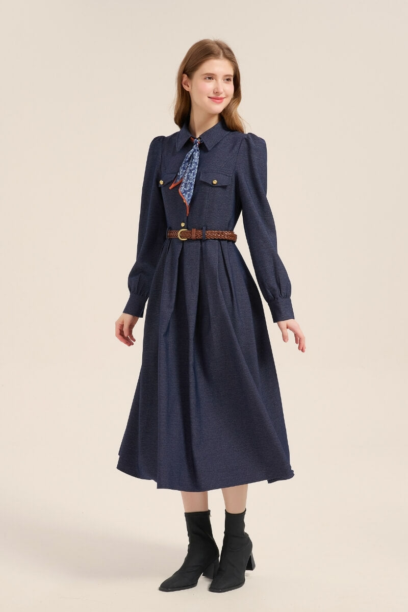 Model wearing a navy twill long sleeve midi dress with structured collar, brown braided belt, and paisley neck scarf, styled with ankle boots.