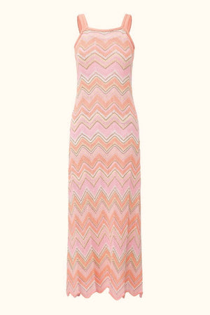 A peach-pink chevron knit maxi dress with wide straps and a fitted straight silhouette, featuring wavy striped patterns in pink, peach, and beige for a summery, handcrafted look.