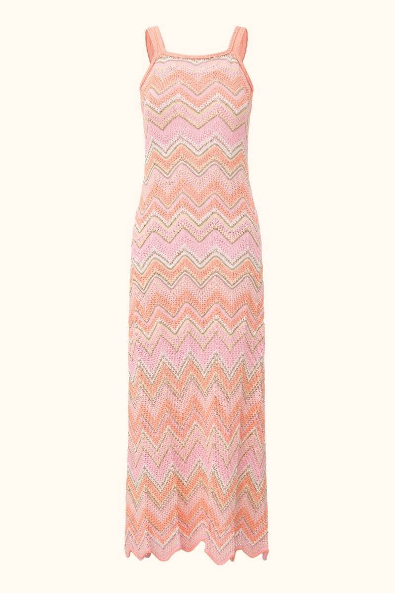 A peach-pink chevron knit maxi dress with wide straps and a fitted straight silhouette, featuring wavy striped patterns in pink, peach, and beige for a summery, handcrafted look.