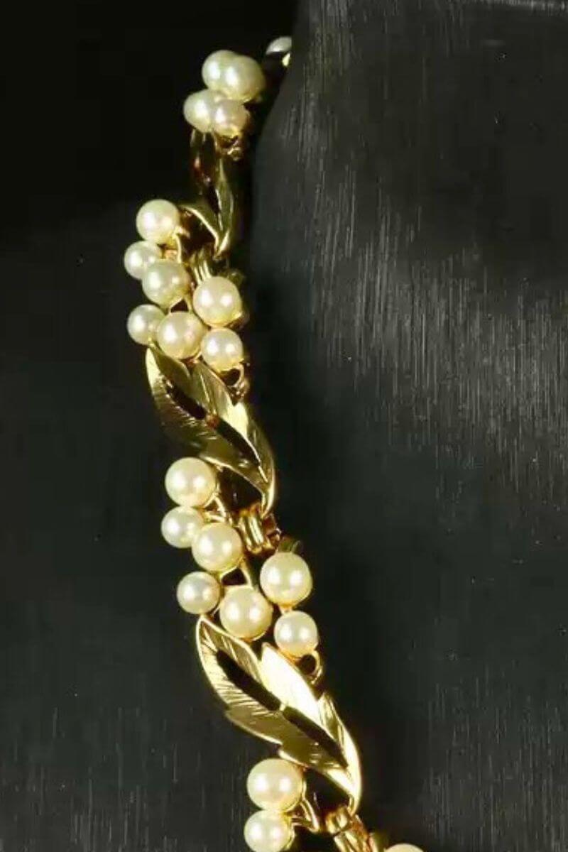 Detailed view of a gold leaf necklace with clustered pearl accents, emphasizing the textured metal and organic arrangement.