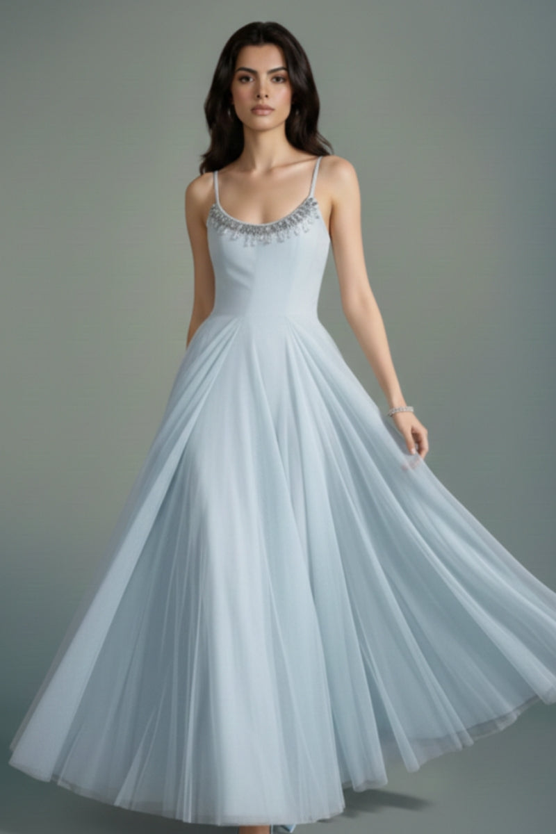 Model wearing a powder blue tulle maxi dress with delicate beaded neckline and flowing A-line skirt, styled with soft waves against a muted studio background.