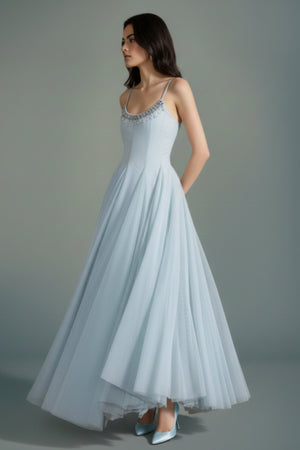 Side view of a powder blue tulle maxi dress featuring a fitted bodice and airy layered skirt, creating a graceful silhouette in motion.