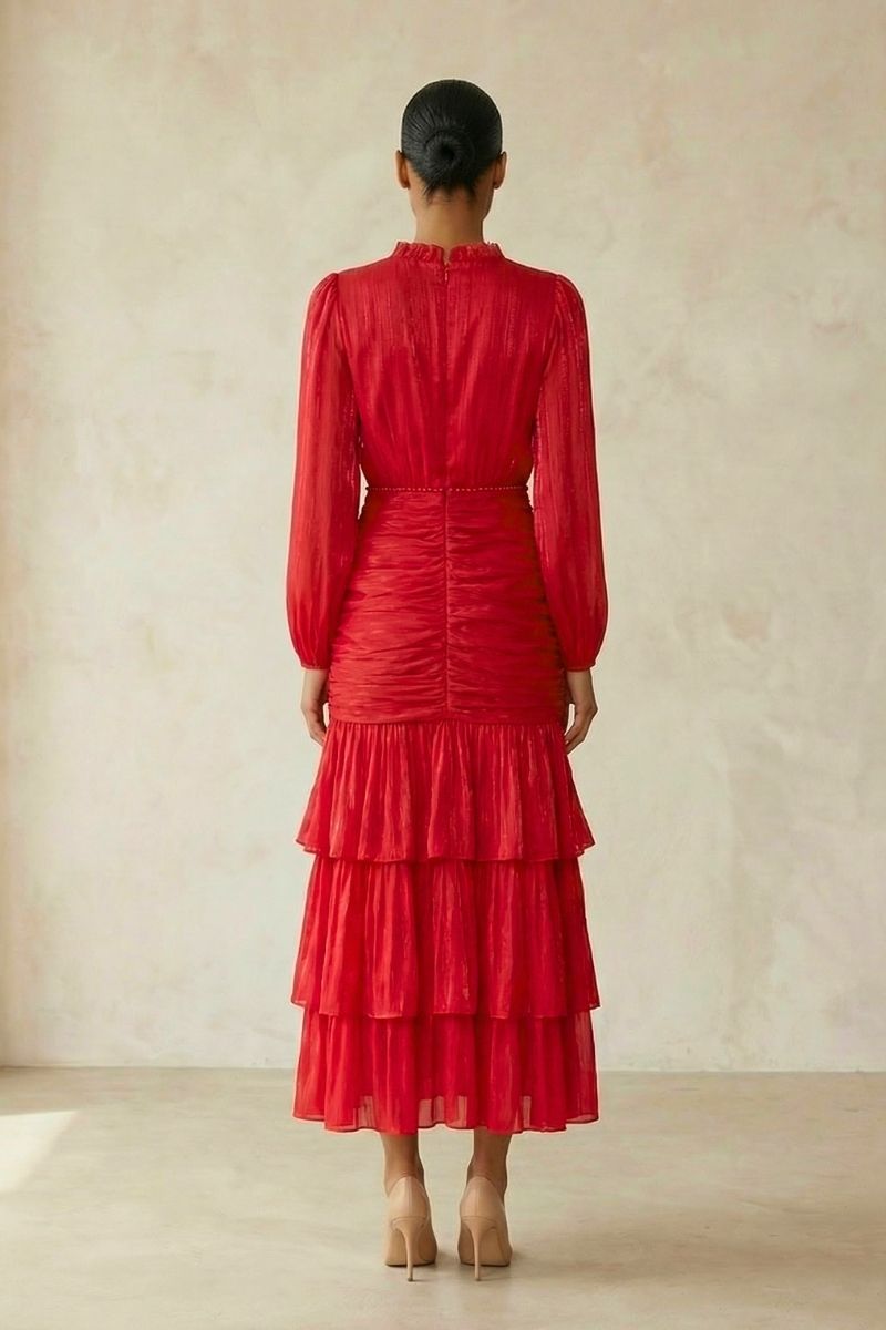 Back view of a red long-sleeve chiffon midi dress showing the ruched bodice and flowing tiered skirt in a neutral-toned studio setting.