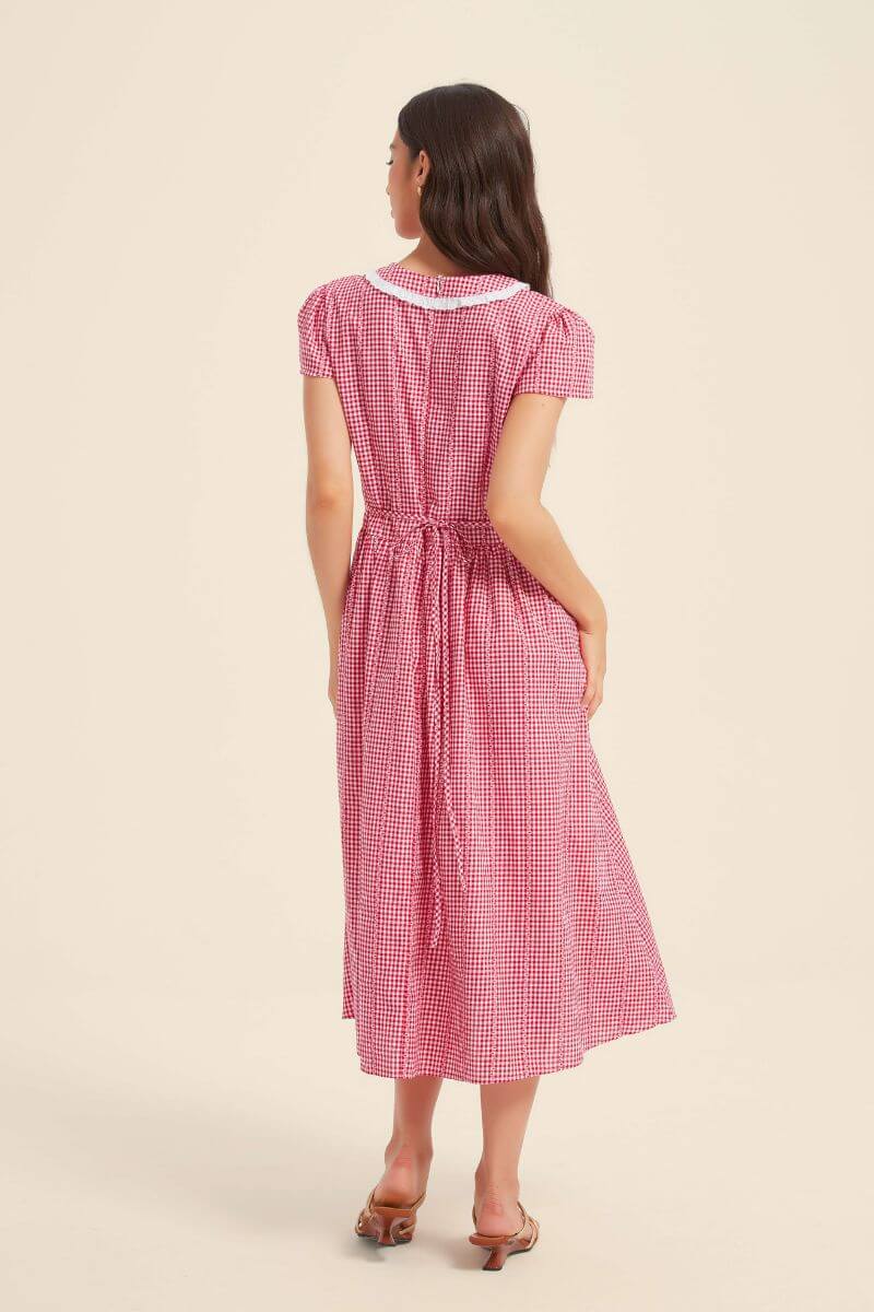 Back view of a red gingham midi dress showing short sleeves, a gathered waist with adjustable tie, and an A-line skirt.