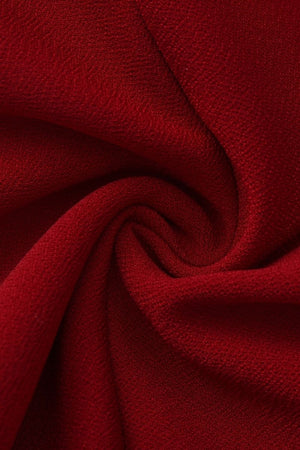Close-up shot of textured red knit fabric showing soft drape and fine woven detail.