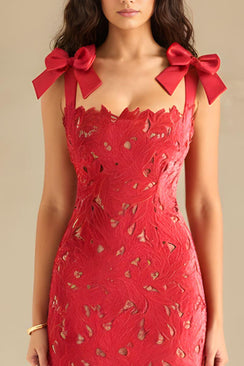 Close-up of the red lace dress showing the scalloped neckline, intricate cutout lace details, and satin bow-tie shoulder straps.