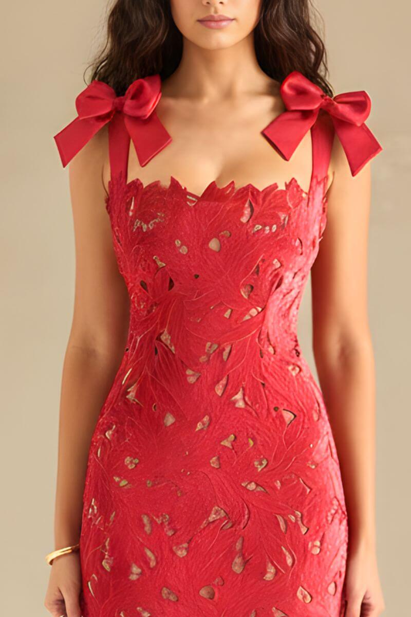 Close-up of the red lace dress showing the scalloped neckline, intricate cutout lace details, and satin bow-tie shoulder straps.