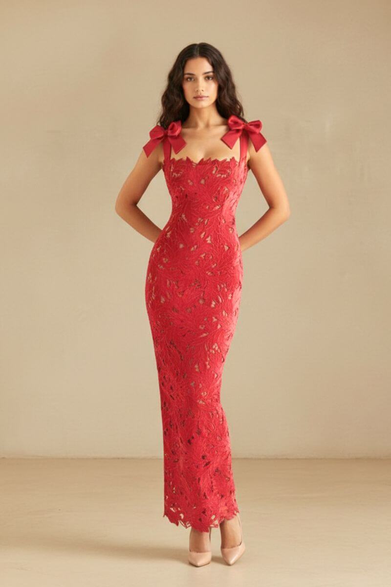 Model posing in a red lace bow-shoulder gown with a body-skimming fit and floral cutouts, hands placed behind her back.