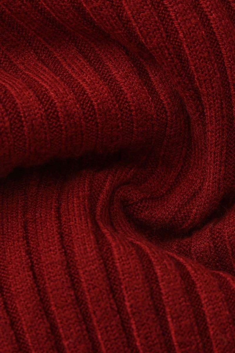 A close-up photo of the red ribbed knit fabric showing the soft, stretchy texture and fine vertical stitching of the sweater.