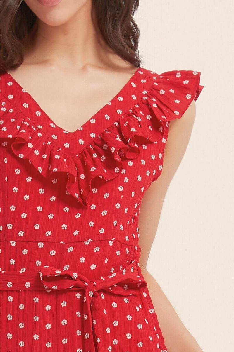 Close-up view of the red ruffle polka dot dress showing the V-neckline, delicate frill trim, and waist tie detail in soft textured fabric.